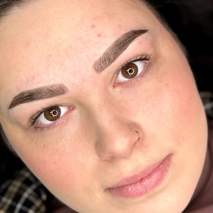 Portrait of a woman with perfected eyebrows framing her eyes, showcasing the quality of the beauty services received.