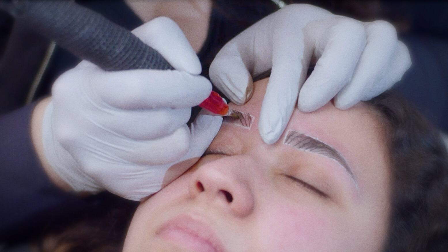 A professional beautician meticulously performs microblading on a client's eyebrows, ensuring precision in a serene salon setting.