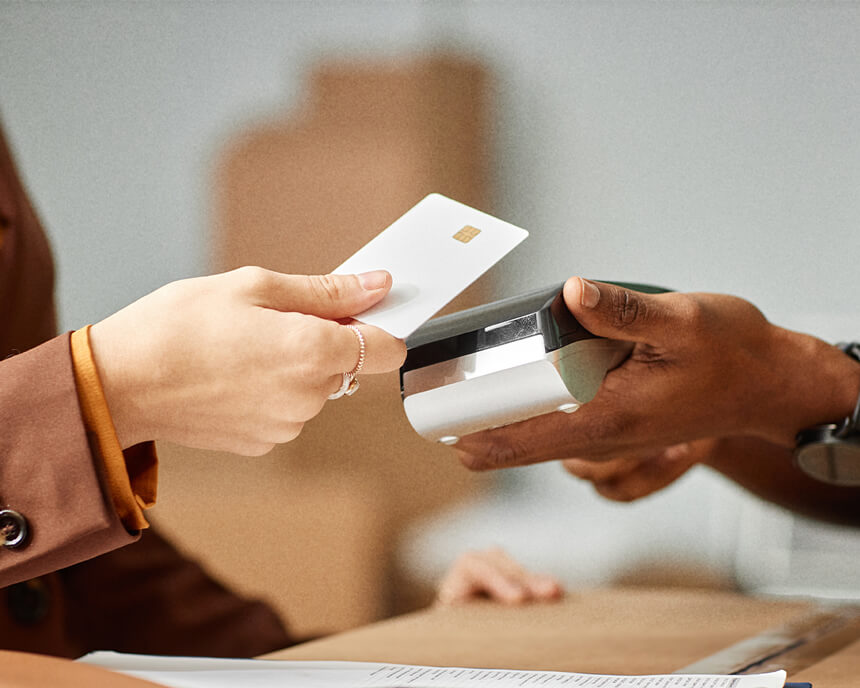 Hands exchanging a credit card over a payment terminal, illustrating a transaction, possibly at a beauty clinic.